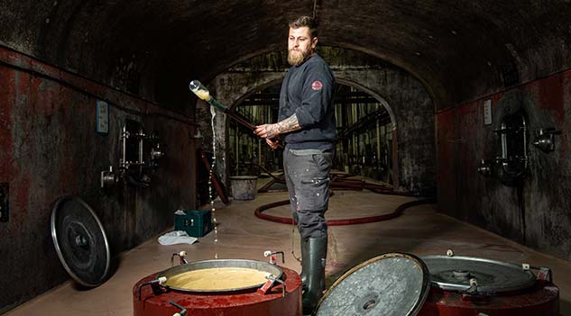 Agricultural manager controlling a wine tank during the vinification process inside a winery